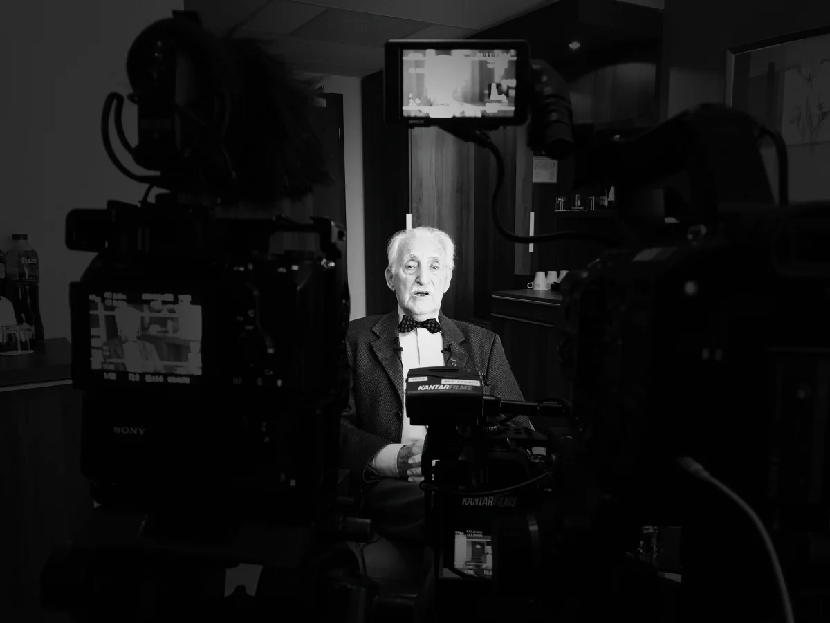Interviewpartner im Lichtkegel, umrahmt von Kameras, in Schwarz-Weiß